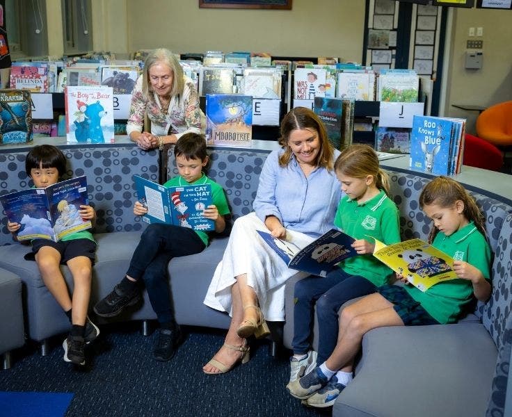 2 teachers reading library books with 4 students reading books