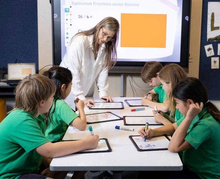 Teacher working with 5 students working on whiteboards
